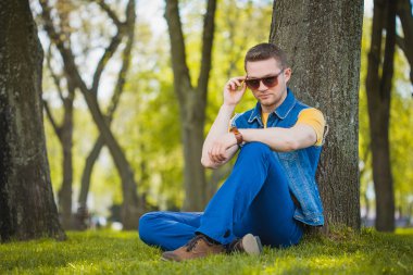 adam parkta yeşil çimenlerin üzerinde oturuyor