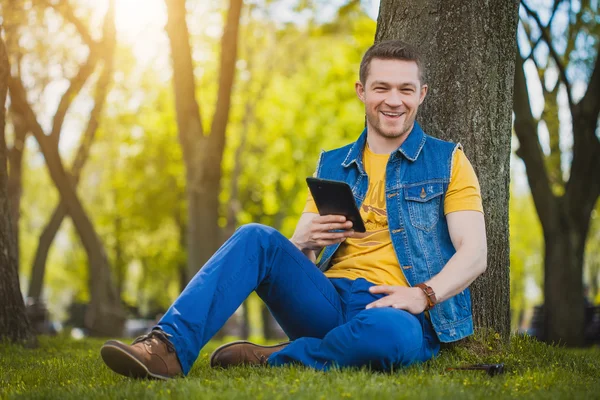 Stilig ung man med tablett i parken — Stockfoto