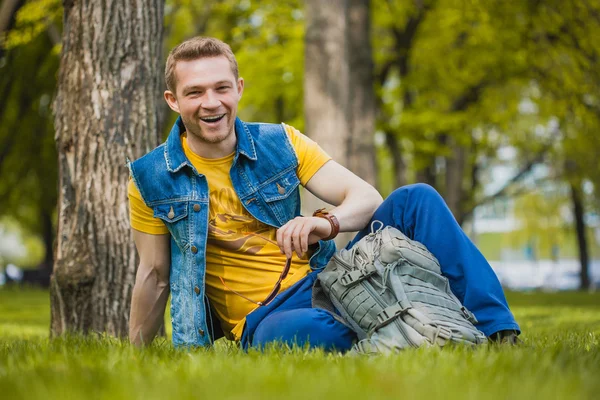 Man is sitting on the green grass in park — Stock Photo, Image