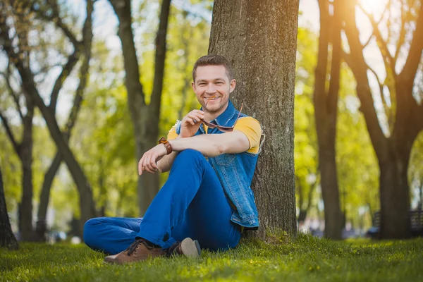 Man is sitting on the green grass in park — Stock Photo, Image