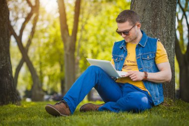 dizüstü bilgisayar ile parkta genç adam