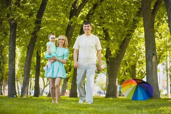 Счастливая молодая семья проводит время в солнечном парке — стоковое фото