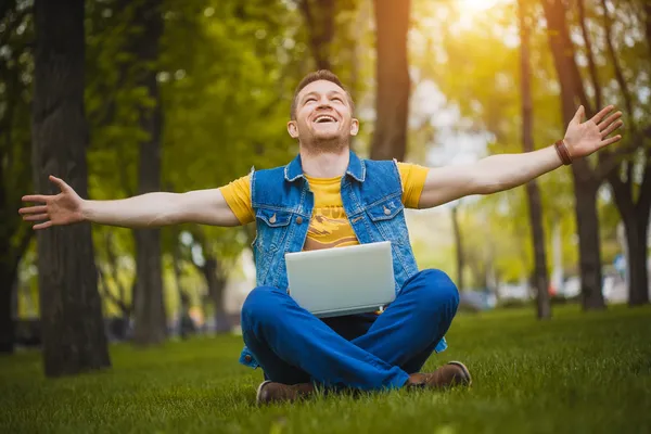 Ung man i parken med en bärbar dator — Stockfoto