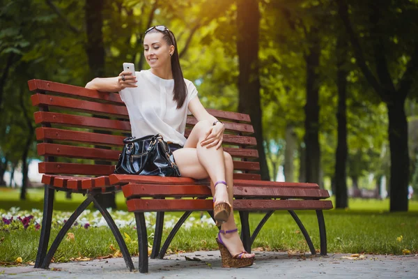 Young Woman with smartphone in the park — Stock Photo, Image