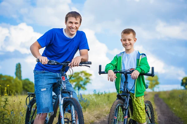 Far og sønn sykler sammen. – stockfoto
