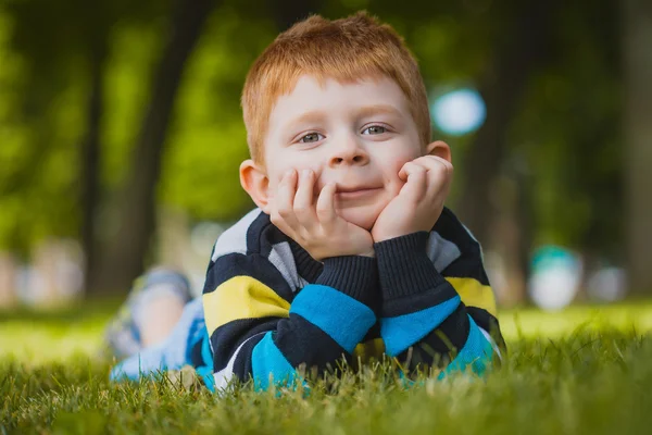 Malý chlapec leží na trávě v parku — Stock fotografie