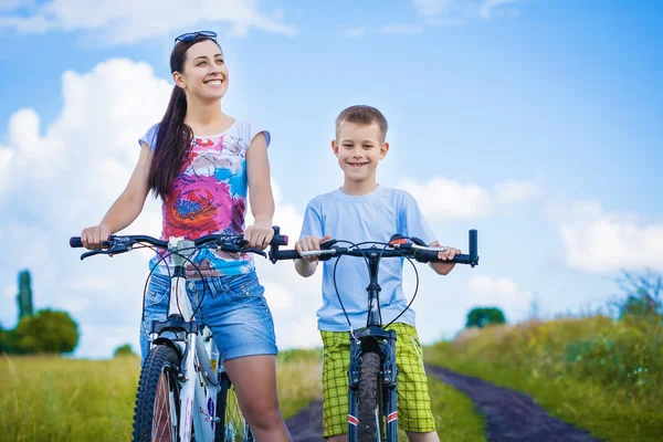 Счастливая мать и сын на велосипеде в поле — стоковое фото