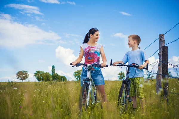 Mother and son riding bicycle in the field — Stock Photo, Image