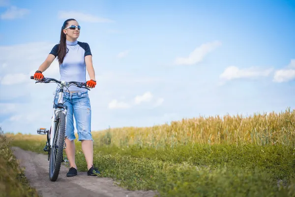 Frau radelt draußen im Feld — Stockfoto