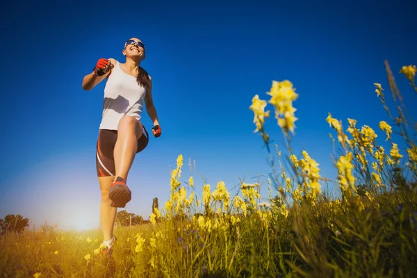 Ung kvinna jogging i fältet — Stockfoto