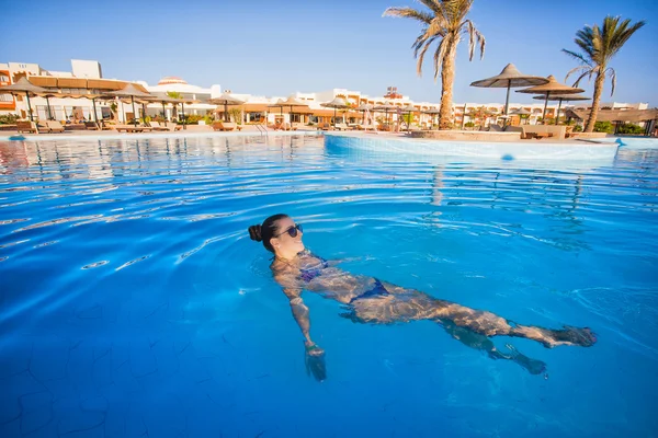 Donna che nuota in una piscina blu — Foto Stock