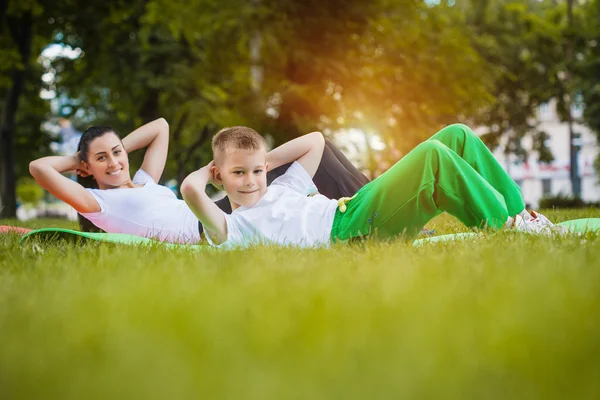 Zoon en moeder doen oefeningen in het park — Stockfoto