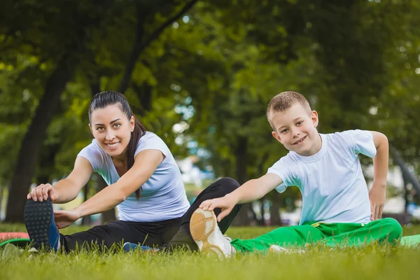 Sønn og mor gjør øvelser i parken – stockfoto