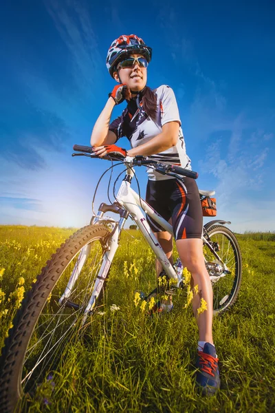 Mulher está andando de bicicleta lá fora no campo — Fotografia de Stock