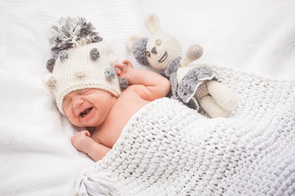 Weinen Niedliches neugeborenes Mädchen mit Strickmütze auf dem weißen Hinterhof — Stockfoto