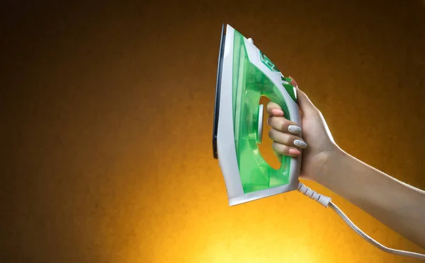 Steam iron in a female hand on a yellow background — Stock Photo, Image