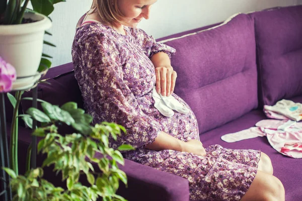 Mujer embarazada sentada en el sofá. esperando al recién nacido. — Foto de Stock