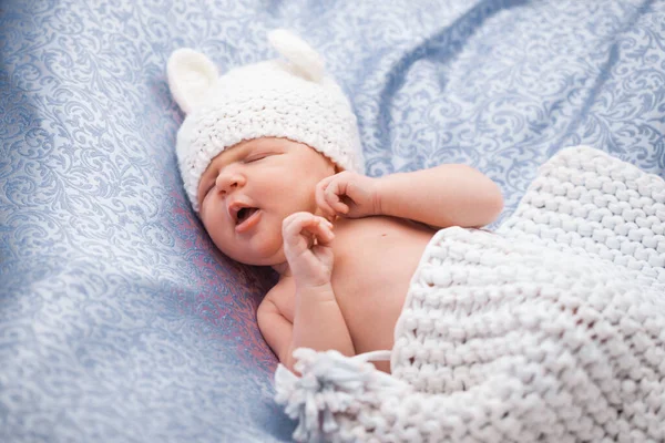 Cute newborn baby girl in a knitted hat on the blue backdround — Stockfoto