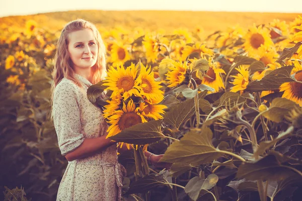 Vrouw met zonnebloemen in een retro jurk en een hoed in een zomer veld — Stockfoto