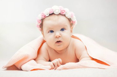 Çiçekli şirin bir bebek. Üç aylık mavi gözlü kız havluya sarılmış.