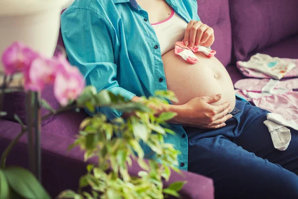 妊娠中の女性がソファに座ってる。新生児を待って. — ストック写真