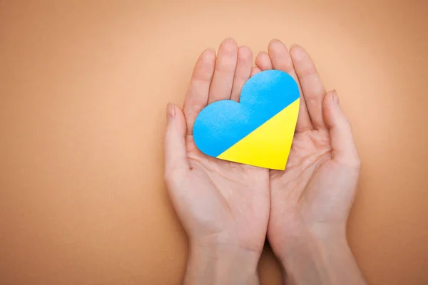 Coeur avec imprimé le drapeau national de l'ukraine entre les mains des femmes. — Photo