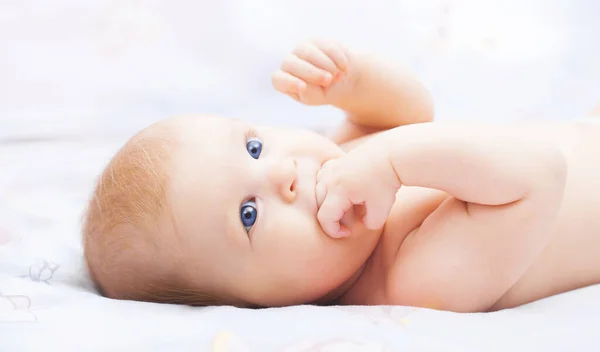 Lindo bebé de ojos azules en su acogedora cama blanca — Foto de Stock