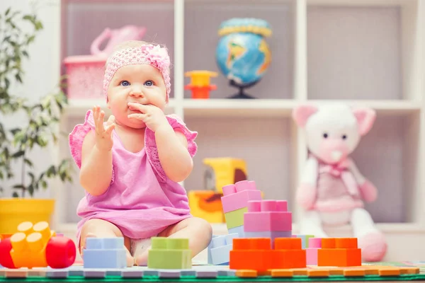Baby girl playing with colourful building blocks at home or kindergarten — Stockfoto