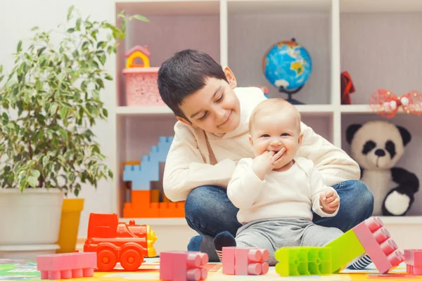Çocuklar evde ya da anaokulunda renkli yapı taşlarıyla oynuyorlar.