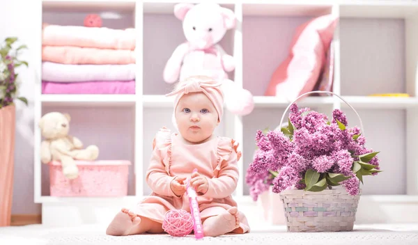 Baby with lilac flowers at home or kindergarten — Stok fotoğraf
