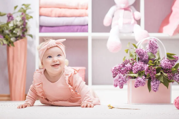 Bebé con flores de color lila en casa o jardín de infantes —  Fotos de Stock