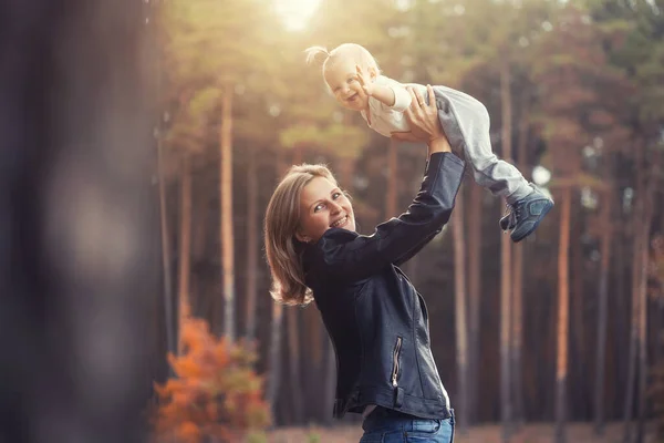 funny family games in the autumn forest, mother throws the child up