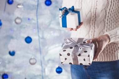 Beyaz kazaklı ve kot pantolonlu tanınmayan bir kadın Noel ağacının önünde.