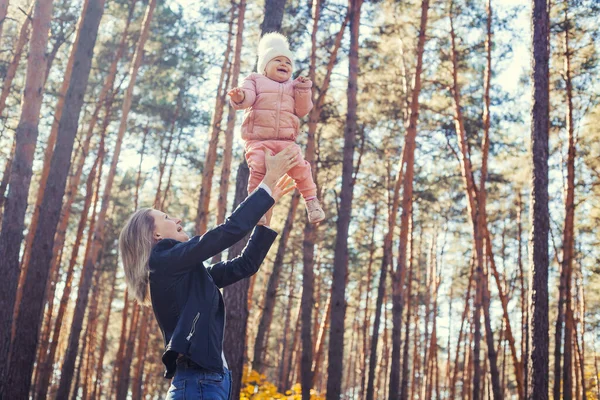 funny family games in the autumn forest, mother throws the child up