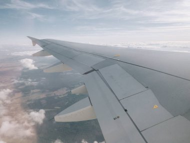 Bulutların üzerinde uçan bir uçağın kanadının ayrıntıları