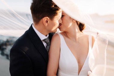 Gelin peçesinin altında gün batımında evli bir çift.