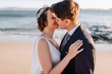 Gün batımında sahilde öpüşen evli bir çift.