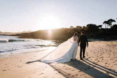 Gün batımında sahilde yürüyen evli bir çift.