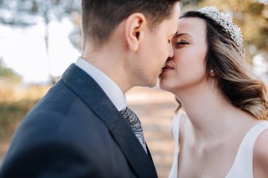 Yeni evli bir çift ormanda öpüşüyor.