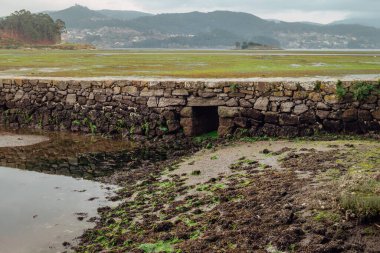 Terk edilmiş tuz düzlüklerinde taşlardan yapılmış su kapısı olan Roma köprüsü.