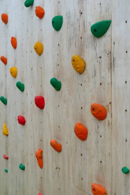 Renkli tırmanışlar bir tahta duvara tutunur.