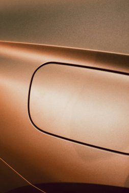 Detail of the fuel tank entry on a golden car with metallic reflections and a square shape