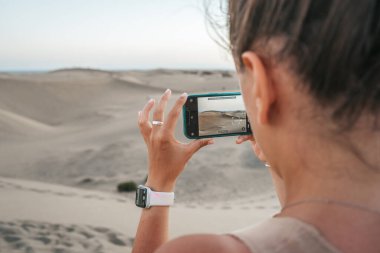 Turist akıllı telefonuyla Maspaloma Çölü 'nde fotoğraf çekiyor.