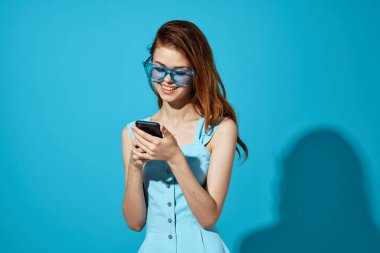 Mavi elbiseli güzel bir kadın. Mavi arka planda telefon var. Yüksek kalite fotoğraf