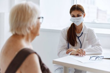Yaşlı kadın hasta, doktor steteskopuyla iletişim kuruyor.