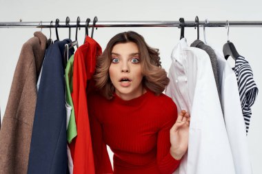 Kıyafetlerin yanında güzel bir kadın moda sektöründe izole edilmiş bir arka plan.