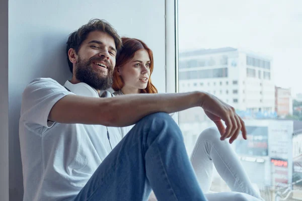 Hombre y mujer se sientan cerca de la ventana con auriculares romance alegría — Foto de Stock