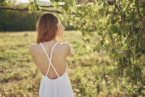 Kadın ağacın yanında poz veriyor.