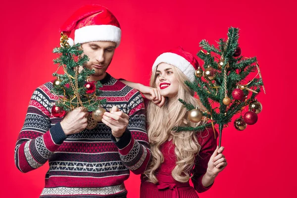 Fröhliches junges Paar im neuen Jahr Kleidung Dekoration Spielzeug roter Hintergrund — Stockfoto