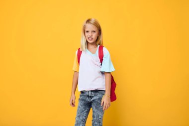 Okul çantalı şık bir kız modern kıyafetler sarı arka plan